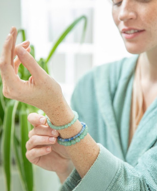 Une femme qui regarde ses bracelets de lithothérapie