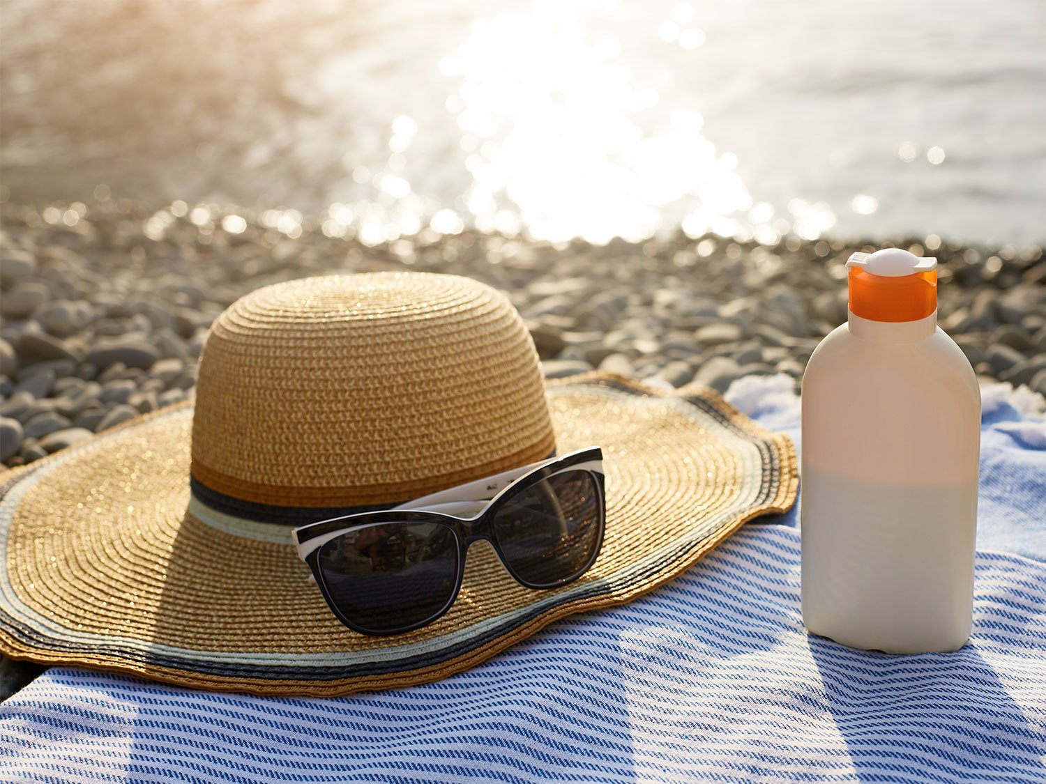 De la crème solaire et des accessoires de l'été sur une serviette de plage
