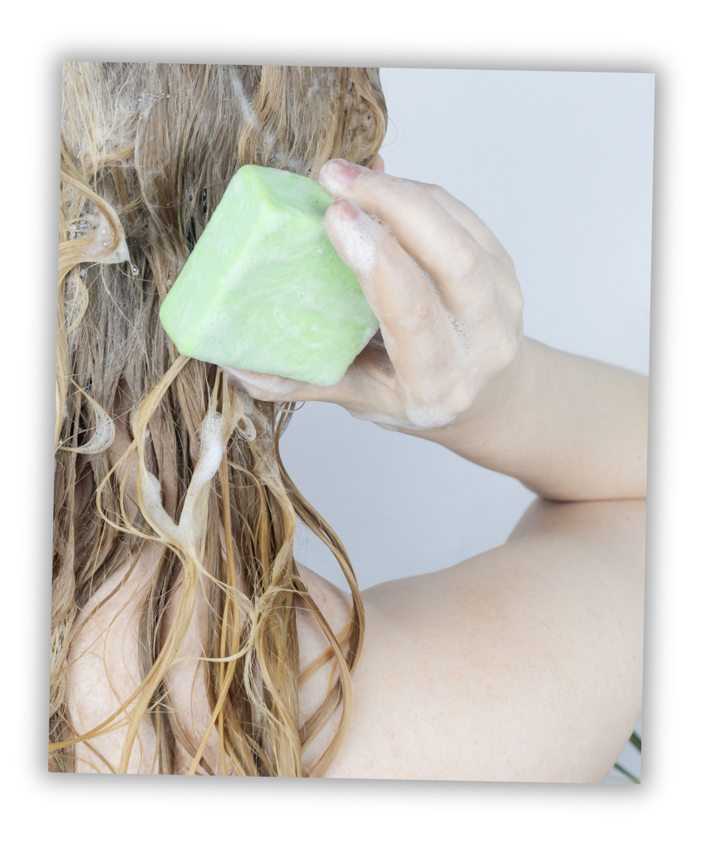 Une femme en train de se laver les cheveux avec un shampoing solide