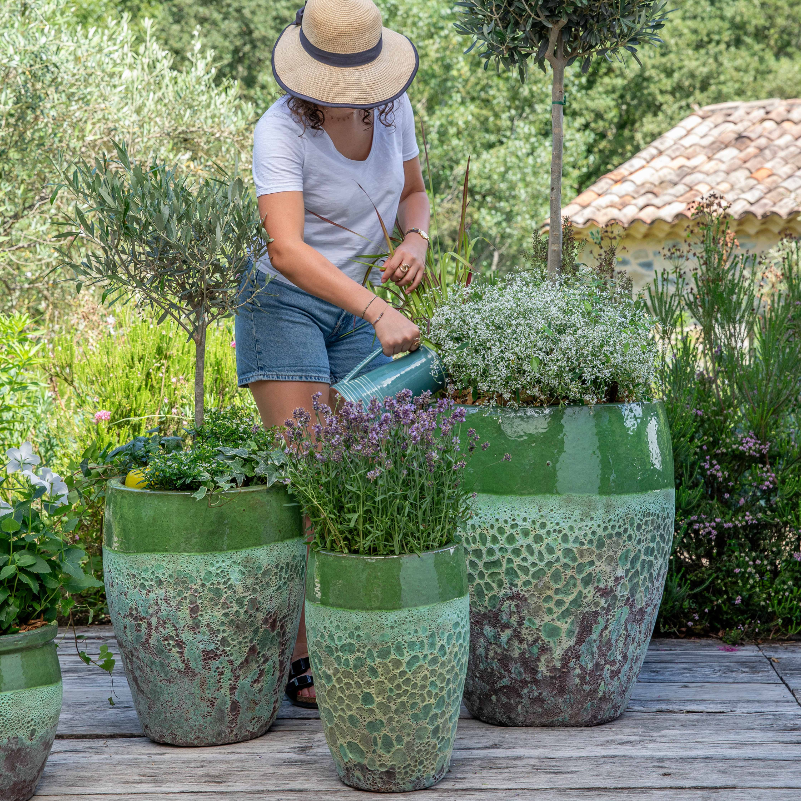 Femme avec un chapeau qui s'occupe de ses plantes d'extérieur