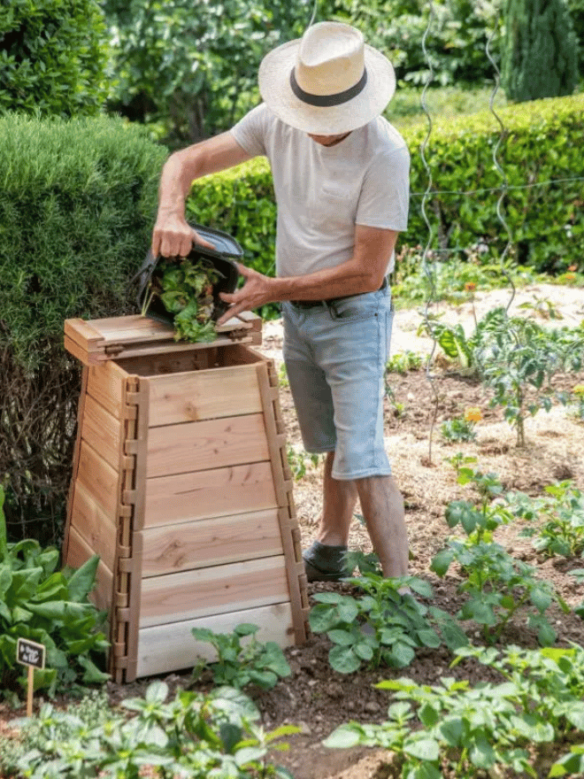 Un homme en train de vider ses déchets organiques dans un composteur