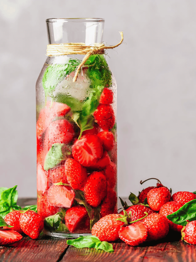 Zoom sur une carafe rempli de fraises coupés et de feuilles de menthe
