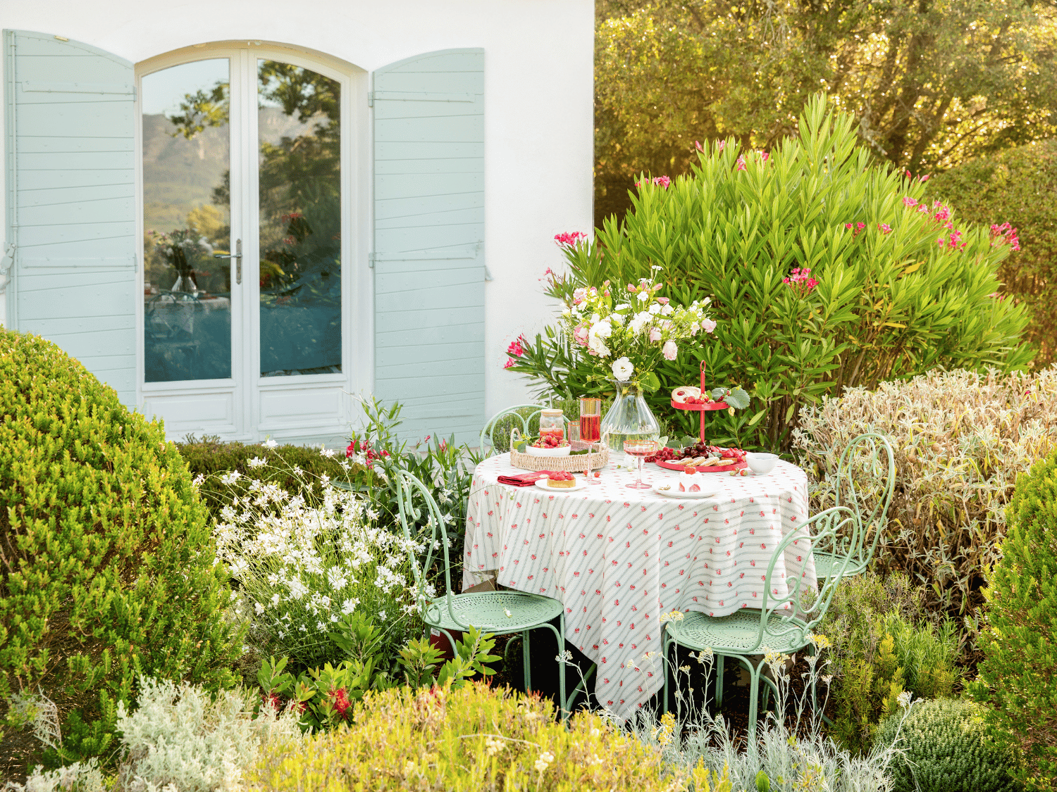 Une table dressée dans le jardin à l'occasion de la fête des mères avec une nappe fleurs et des accessoires colorés
