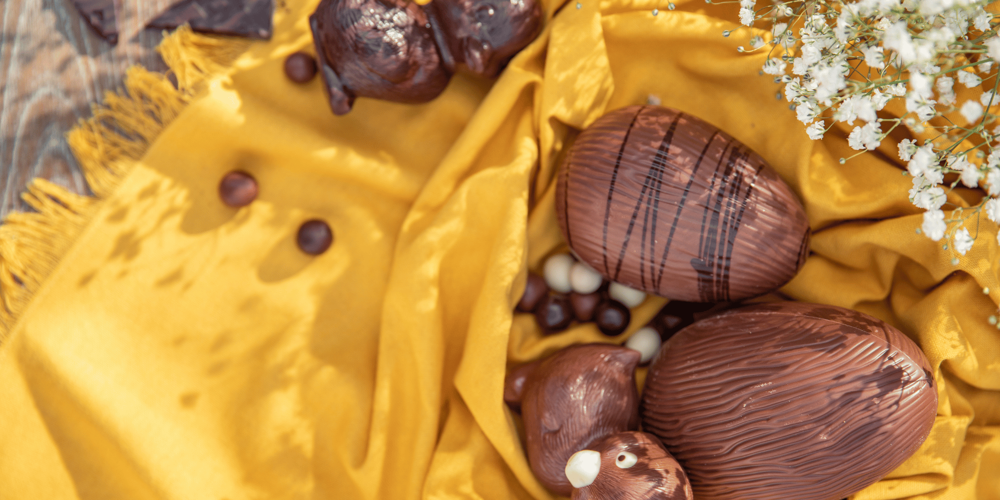 Un drap jaune sur une table avec des oeufs et canards en chocolat