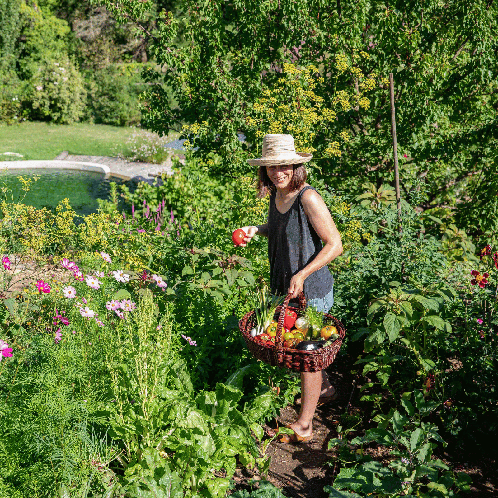 Une femme récolte ses légumes dans son jardin