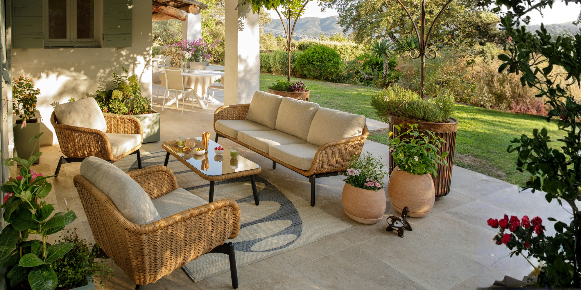 Salon de jardin Aralia sur une terrasse aménagée avec des pots, des végétaux, un tapis