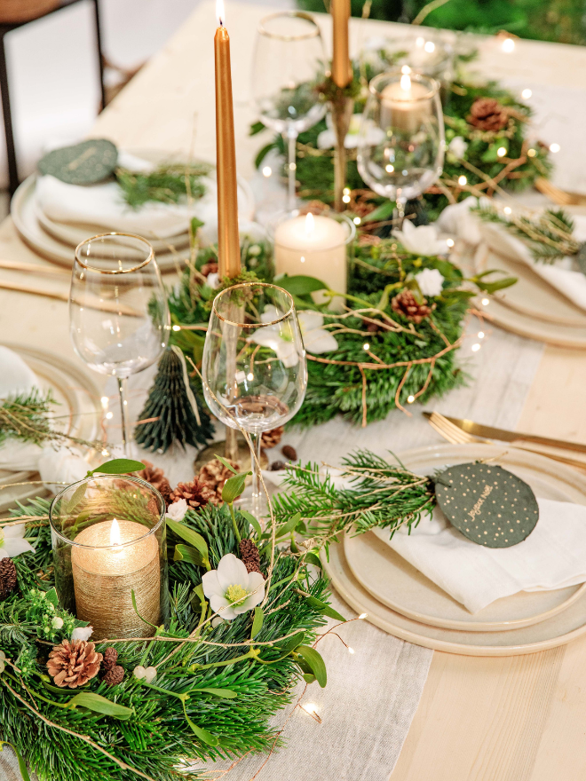 Une table de noël végétalisée avec un centre de table, des bougies et des pommes de pain