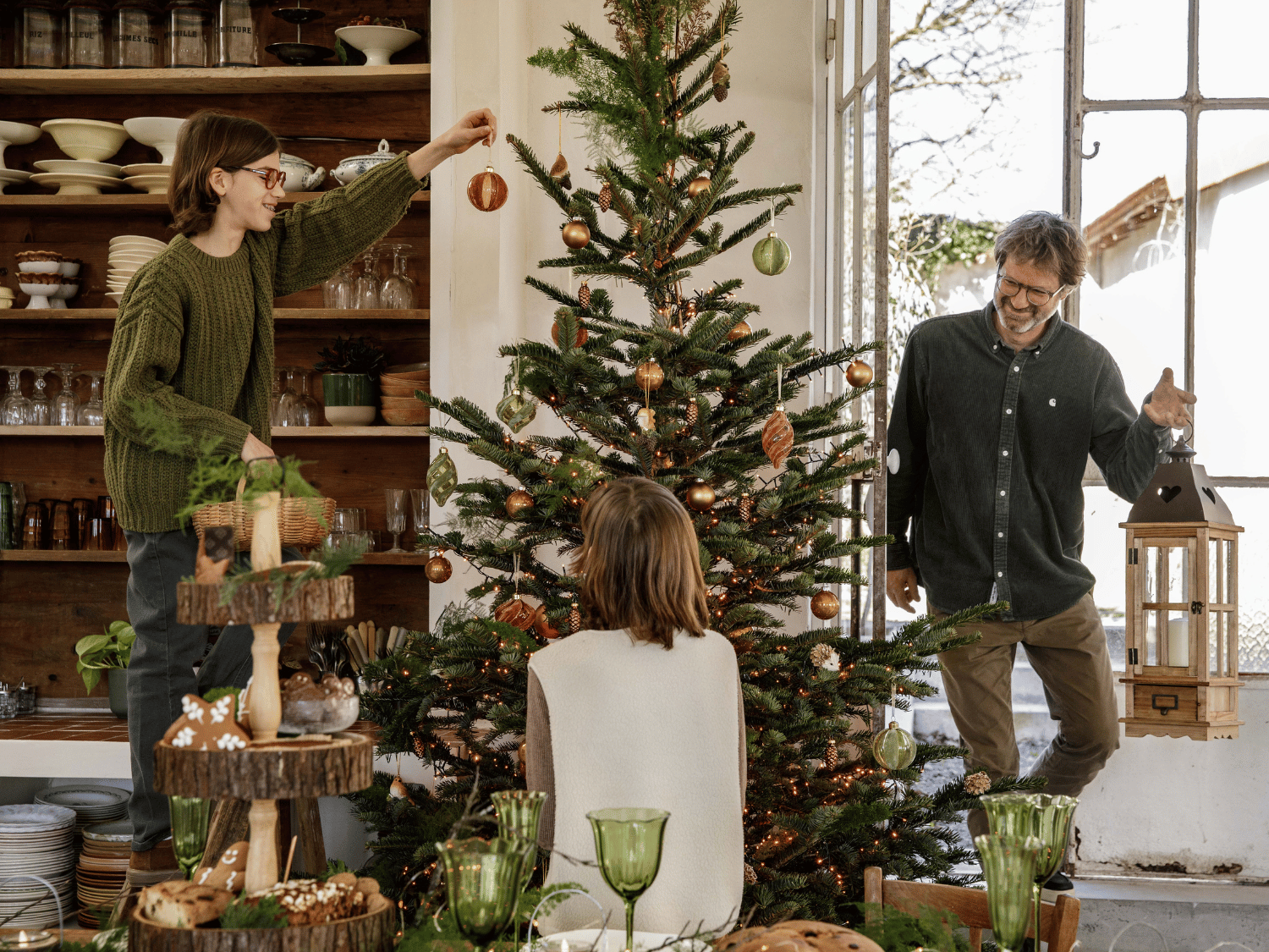 Trois personnes qui décorent le sapin en famille pour Noël