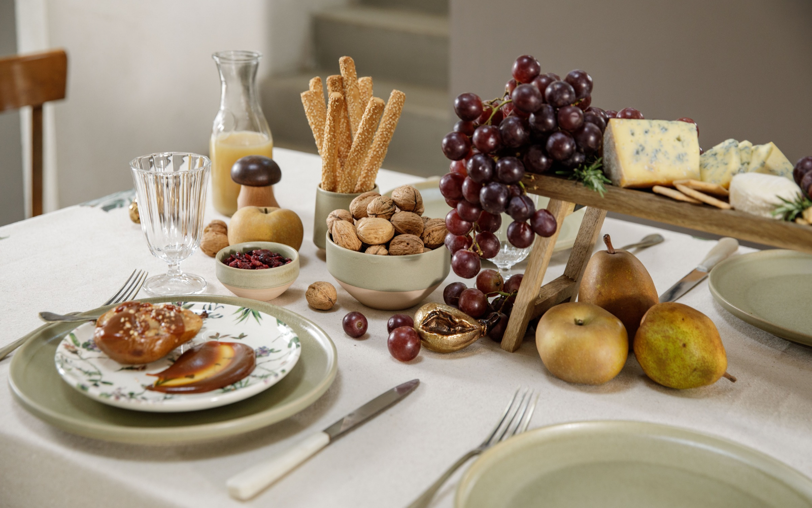 Une décoration de table d'automne comprenant des assiettes, verres, framages, noix, raisins et poires