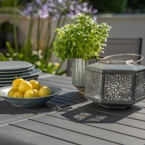 Une lanterne grise posée sur une table de jardin
