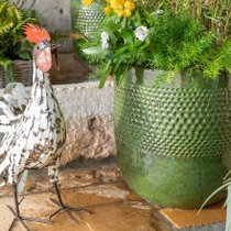 Un cop décoratif à côté d'un pot vert en terre cuite émaillé sur une terrasse