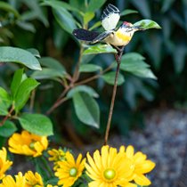 Zoom sur une décoration à planter en forme d'oiseau dans une plante fleurie jaune