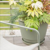 Zoom sur un pot vert kaki sur une terrasse aux allures modernes