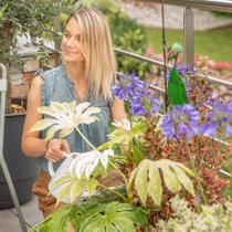 Une femme en train de sourire devant un pot fleuri