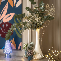 Un vase décoré avec du gypsophile et des guirlandes lumineuses