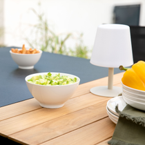 Un bol de concombre et une lampe d'extérieur posés sur une table de jardin