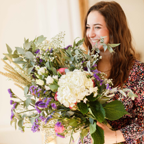 Une femme souriante tient dans ses mains un bouquet de fleurs.