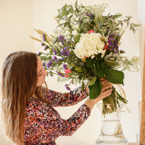 Une femme met un bouquet de fleurs dans un vase.