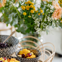 Une salade de fruits dans un bol et un bouquet de fleurs.