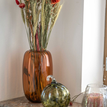 Des fleurs séchées dans un vase, et une citrouille en verre