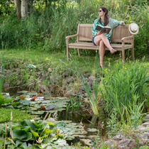 Une femme au bord d'une mare dans son jardin