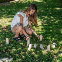 Une fille qui ramasse les quilles du molkky