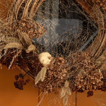 Une couronne de fleurs sechées suspendue à une porte