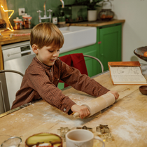 Un enfant qui étale une pâte avec un rouleau