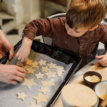 Un enfant qui dépose ses sablés de Noël sur une plaque de cuisson