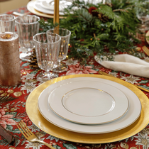 Une table de fêtes dressée pour Noël avec des asiettes blanches et dorées