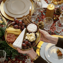 Une femme en train de servir un plateau de fromage pendant un repas de fêtes