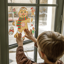 Un petit garçon en train de mettre une vitrophanie sur les vitres pour les fêtes de Noël