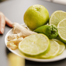 Une assiette posée sur une table avec du citron vert, du gingembre et un piment