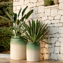 Deux gros pots vert et blanc contre un mur en pierre