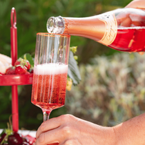 Une personne entrain de servir une coupe de champagne vin pétillant rosé