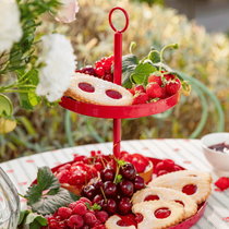 Le présentoir rouge Samina 2 étages sur une table avec des gourmandises sucrées, petits fruits rouge et biscuits à la confiture
