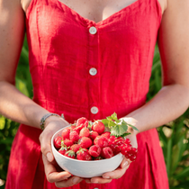 Une femme qui tient dans ses mains une coupelle rempli de fruits rouges du jardin