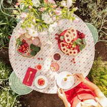 Une décoration de table dans le jardin vue dessus sur laquelle il y a des gourmandises à manger, de la vaisselle et un bouquet de fleurs