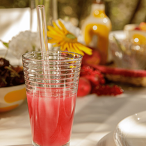 Un jus de fruits de couleur rouge dans un verre avec une paille en verre