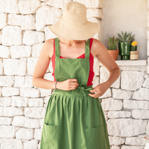 Une femme sur sa terrasse avec un chapeau de paille en train de nouer son tablier autour de sa taille