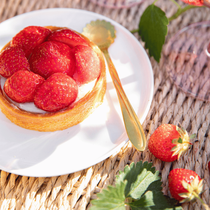 Une tarte aux fraises présenté dans une petite assiette avec une cuillère dorée