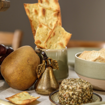 Une décoration de table en forme de poire, avec un bol de crackers, un fromage de chèvre et des apéritifs
