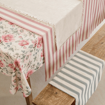 zoom sur un coin de table avec une nappe fleurie et un torchon rayé