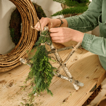 Une femme qui fabrique une étoile de noel en branche de bois