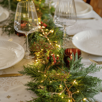 Un centre de table avec des branches de sapin et des guirlandes
