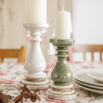 Une table décorée avec deux bougeoirs artisan de couleur blanc et vert, ornés de bougies blanches