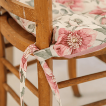 La galette de chaise Exquise Noblesse au motif fleuri nouée sur une chaise en bois