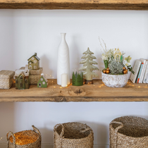 Une étagère avec pleins de décorations de Noël, de plantes et de guirlande dans les tons de vert et brun