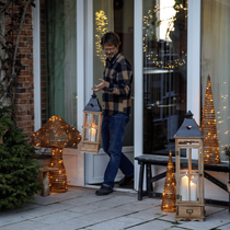 Un monsieur qui sort d'une maison avec une lampe en main