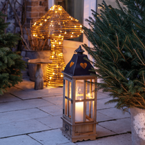 Une lanterne posée à l'extérieur, à côté d'un sapin